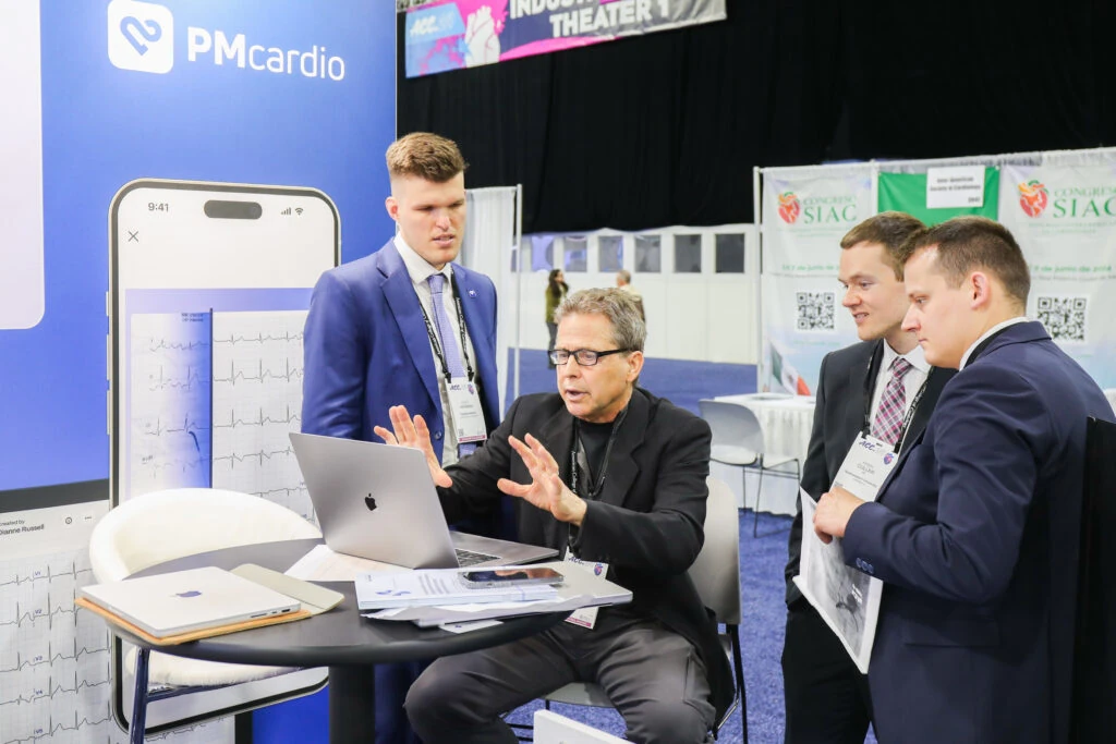 Steve Smith MD demonstrating PMcardio on a laptop to attendees at the ACC.24 booth