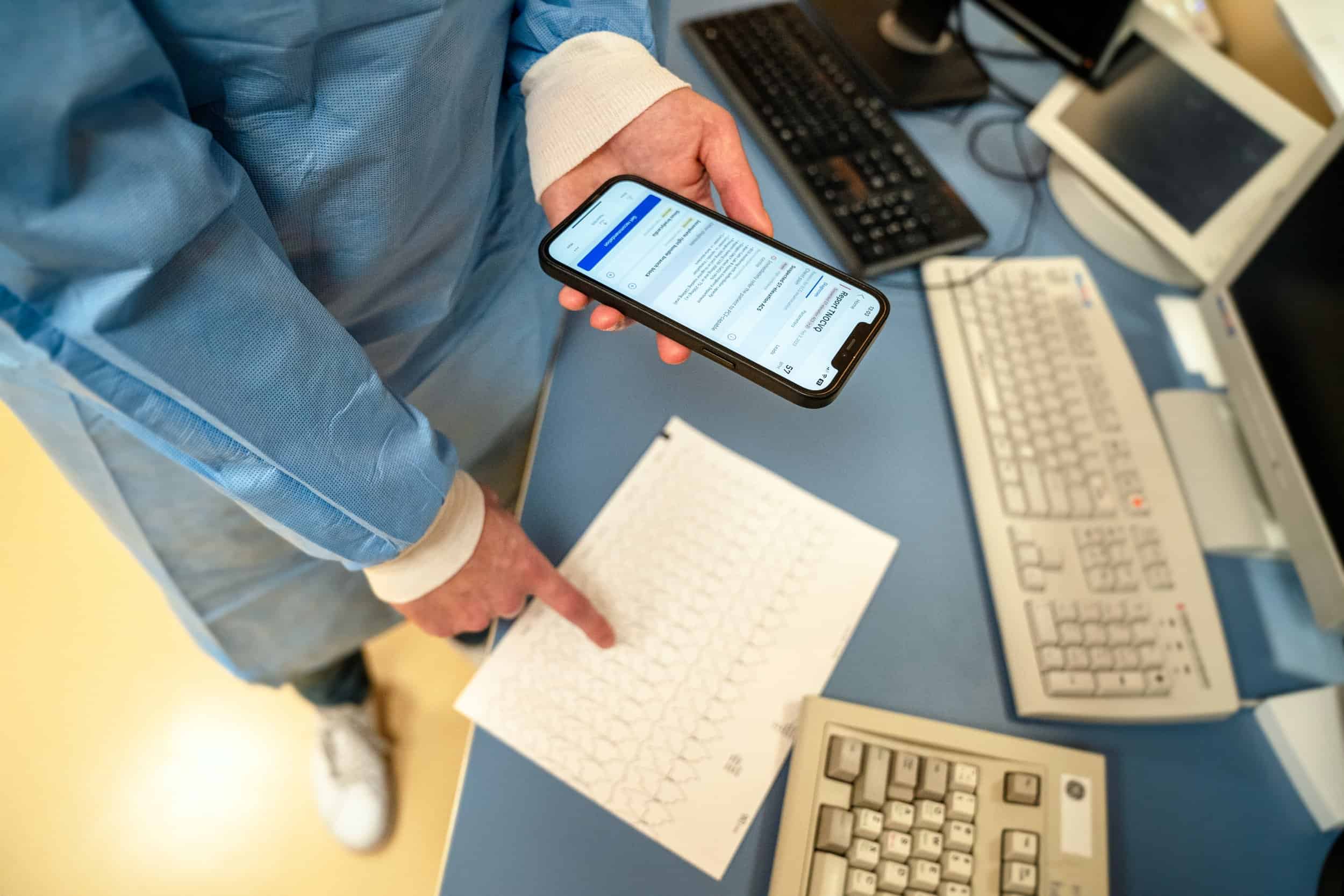 An image of a doctor scanning an ECG with his phone via the PMcardio app
